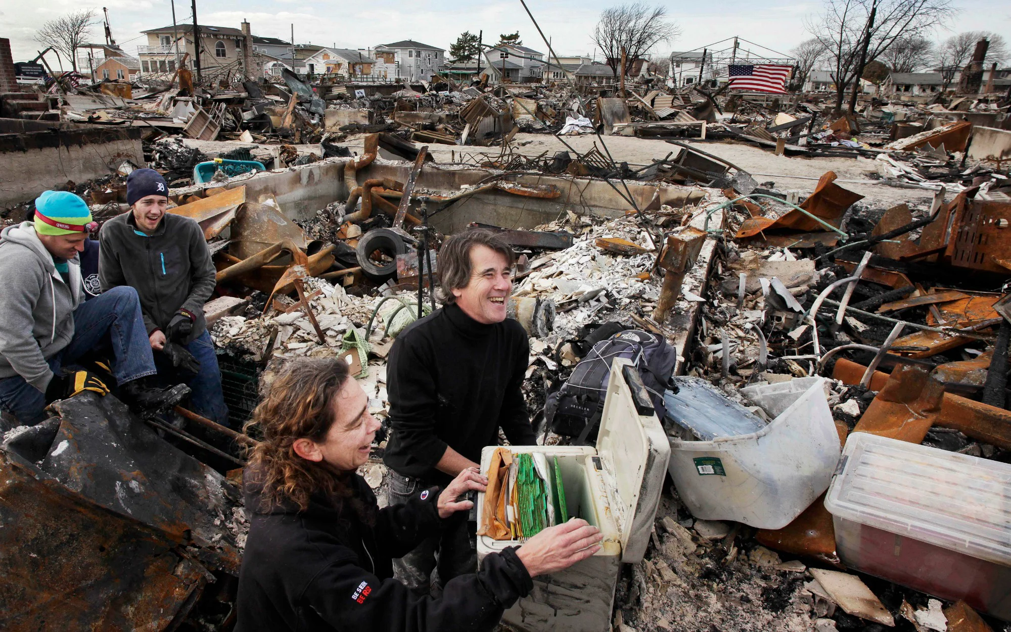Kevin Striegle and another volunteer lifting a family's recovered safe from the rubble of a fire-destroyed home after Hurricane Sandy in Breezy Point, New York.